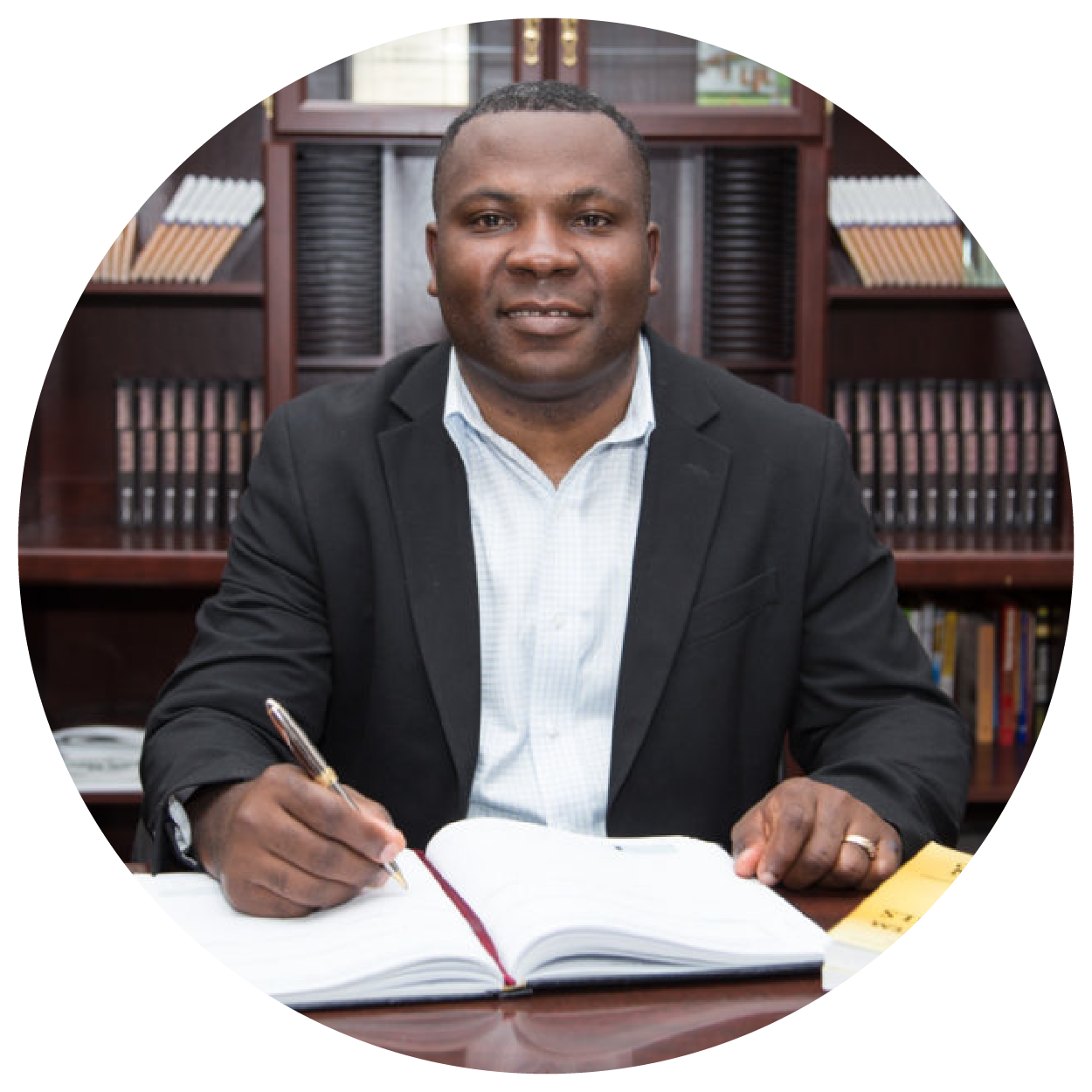 Benson Agbortogo, creator of the Consistent Profit Tree System, seated at a desk with open books in an office.